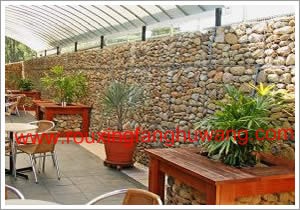 咖啡厅内摆放着花盆的桌子后边的装饰石笼网墙