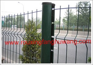 种植着各种鲜艳的花朵的绿化带边上的采用绿色浸塑立柱安装的浸塑焊接高速公路护栏网